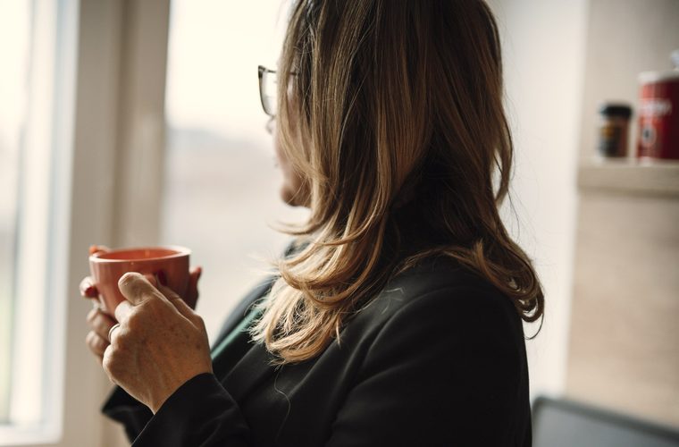 A woman at home by the window, at ease. Her plan is done